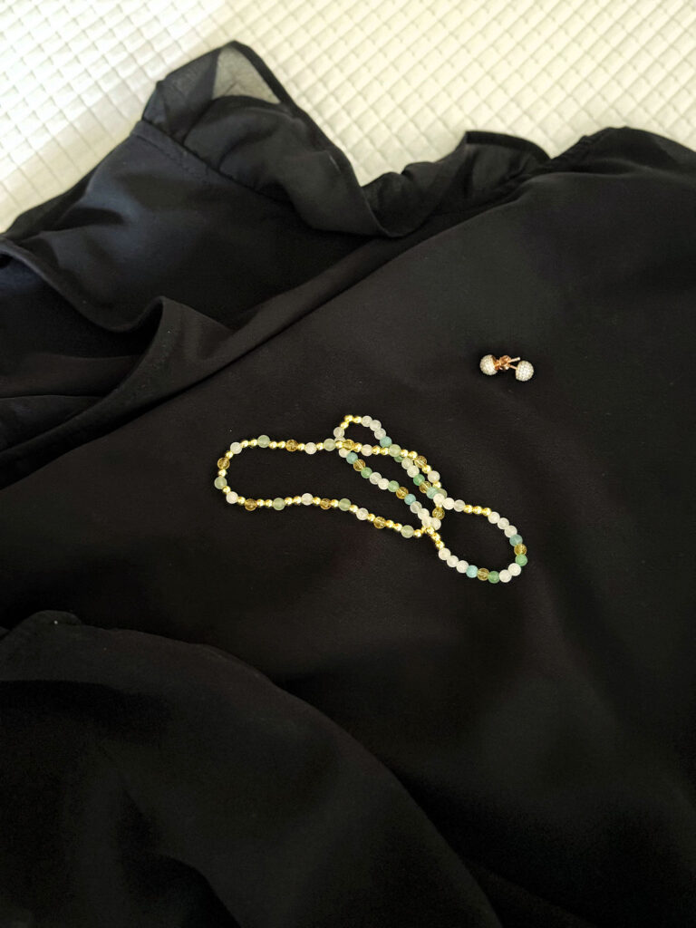 Urlaubsoutfits- schwarze Leinenshorts-schwarze seidige Bluse mit Rüschen-schwarze Sandalen