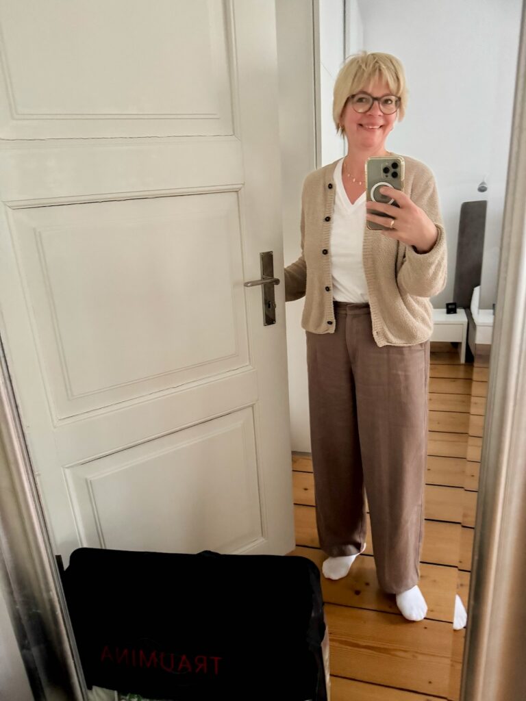Outfitinspirationen-17.Wo 26-Übergangsoutfit-Transitional Garderobe-lifewithaglow-Hose weit in Taupe- weißes T-Shirt mit V-Ausschnitt-Strickjacke im Bouclé Stil-Sneaker-Armbänder Pera Schmuckmanufaktur