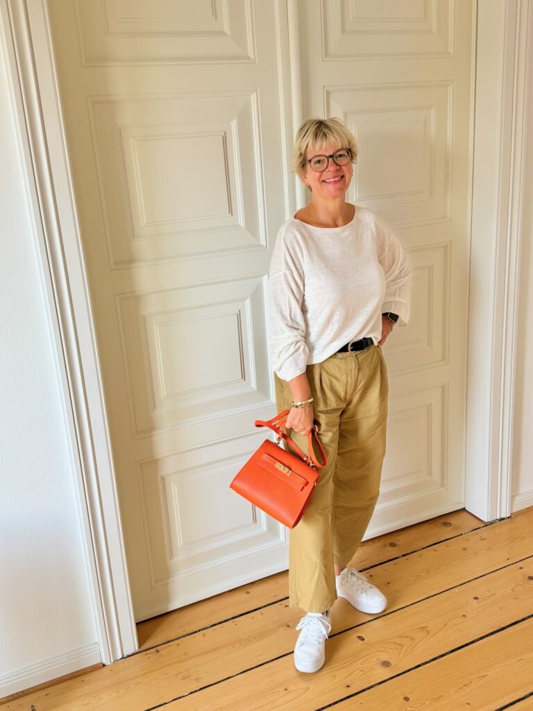 Outfitinspirationen-Sommeroutfits bei wechselhaften Temperaturen-lifewithaglow-weite Hose schilfgrün cropped-leichter Pullover weiß aus mercerisierter Baumwolle- Sneaker weiß-Tasche orange