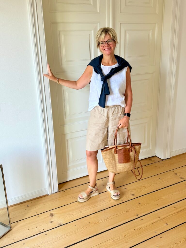 Outfitinspirationen-Sommeroutfits bei wechselhaften Temperaturen-lifewithaglow-Leinenshorts beige-weißes Blusentop aus Leinen-Cardigan Leinen-Baumwollmix-Bastsandalen mit kleinem Plateau-Korbtasche- hellblaue Armbänder Pera Schmuckmanufaktur